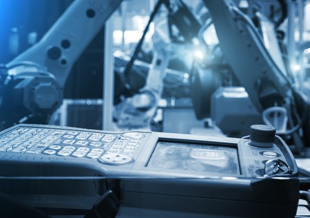 Digital Controller For Robot in Factory against the background of blurred yellow industrial robotsの写真素材