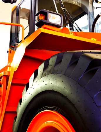 Details of modern red tractor close up, bottom view, black tires