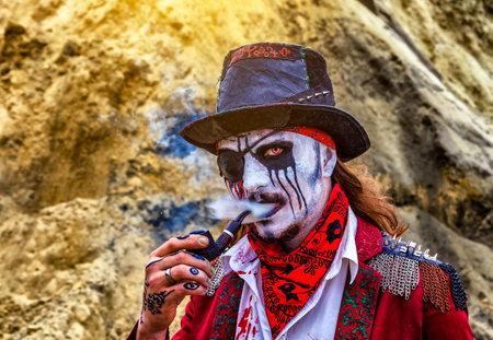Halloween concept. one-eyed robber with a bandage in a black hat, a leaking eye and blood on a white...
