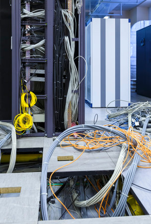 process of installation and cabling in modern data center. Server rack with skeins of cables next to...