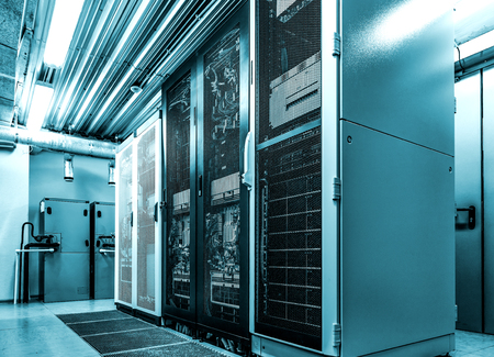 Datacenter server racks with network computers in neon blue toning. Room with several of mainframe hardware and supercomputers in big data centerの写真素材