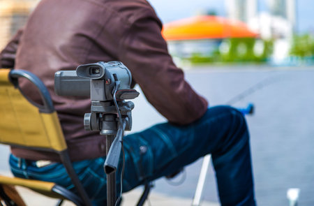 Close up of video camera filming young male blogger at city pond