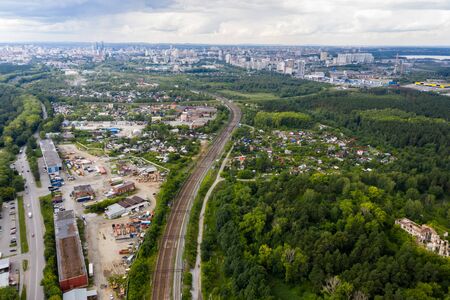 The city skyline in the distance in foreground, railway, industrial area and a forest with houses. Yekaterinburg, Russiaの写真素材