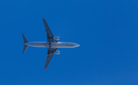 medium size blue passenger airplane on clear sky background. bottom view a few seconds before...