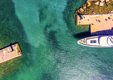 waterfront port of Rhodes Mandraki, clear sea rocky bottom, yachts cars top view from droneの写真素材
