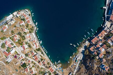 Aerial panoramic view on beautiful Greek houses on island hills, yacht sea port, tourist ferry boat at Aegean Sea bay. Greece islands holiday vacation tours tripの写真素材