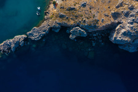 Aerial top view of sea waves hitting rocks on the beach with turquoise sea water. Amazing rock cliff...