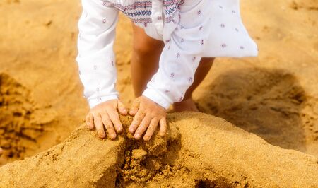 baby playing at beach. childs hands close-up build top of sand castle, selective focusの写真素材