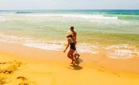 Happy beautiful family on tropical sandy shore of the ocean with yellow sand holiday vacationの写真素材