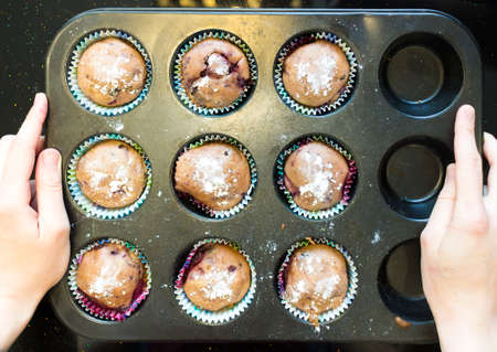 women's hands hold the shape for baking cupcakes. Carrot muffins in metal baking form. Homemade tasty dessert or breakfast. Healthy eating concept.の写真素材