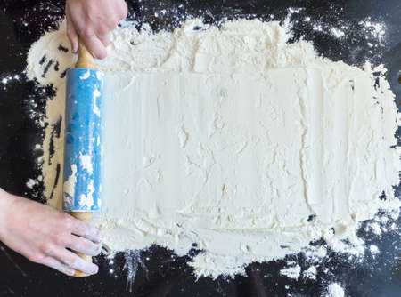 Rolling pin in woman hands and white flour on dark backgroundの写真素材