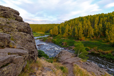 soft sun rays in evening over beautiful valley with a mountain river and many rapids. Ural, Russia,