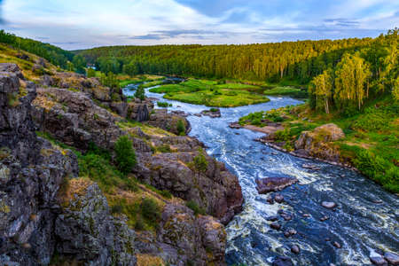 swirling streams of mountain river with a rocky shore in a beautiful valley in forest, top view.の写真素材