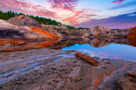 Ural Mars surreal alien landscape. Cracked dried-up bottom of clay pit and high mountains. Fantastic high mountains against a clear blue sky. High red mountains on orange cracked ground.の写真素材