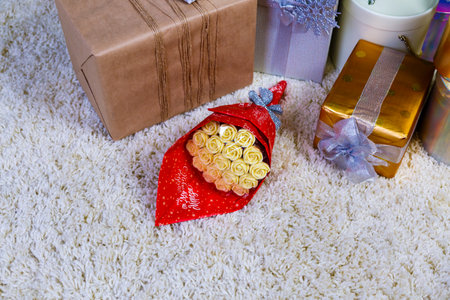 bouquet of pink chocolate roses among the gifts on fluffy white rug under Christmas treeの写真素材