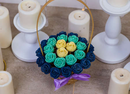 basket with chocolate flowers roses on a white background among candles, fireplace, sweet gift, edible flowers.の写真素材