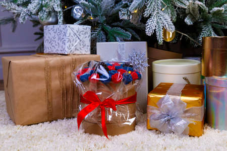 Christmas gifts under the Christmas tree red and wooden toys brick wall, in foreground bouquet of chocolate flowersの写真素材