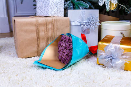 Christmas gifts under the Christmas tree red and wooden toys brick wall, in foreground bouquet of chocolate flowersの写真素材