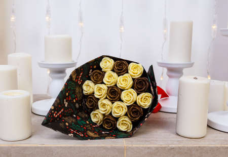 bouquet of roses made of chocolate lies on the marble base of fireplace among candles.の写真素材