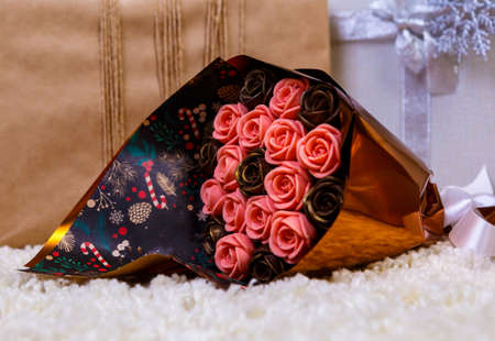 boxes with Christmas gifts under the blue Christmas tree, in foreground a bouquet of chocolate flowersの写真素材