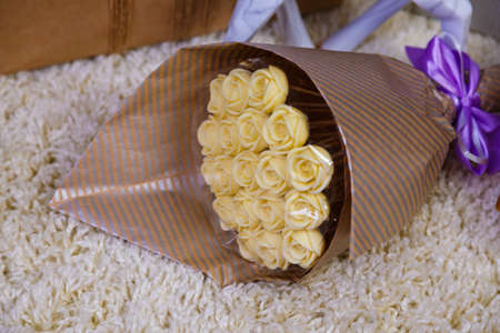 Christmas gifts under the Christmas tree red and wooden toys brick wall, in foreground bouquet of chocolate flowers.の写真素材