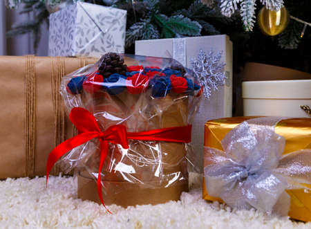 round box bouquet with flowers roses on the background of gift boxes with ribbons at Christmas treeの写真素材