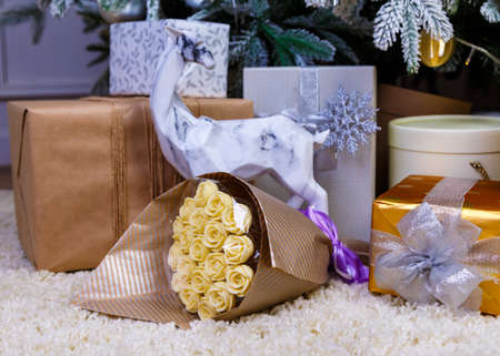Christmas gifts under the Christmas tree red and wooden toys brick wall, in foreground bouquet of chocolate flowersの写真素材