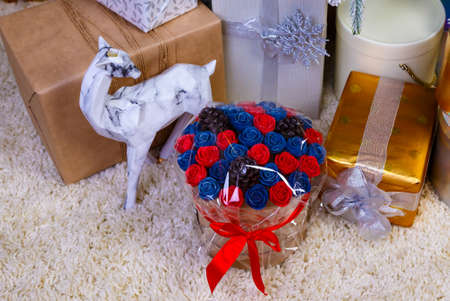 round box bouquet with flowers roses on the background of gift boxes with ribbons at Christmas treeの写真素材