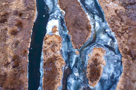 Aerial texture of a frozen river without snow on ice, a vertical view from a drone, colorful streams with islands.の写真素材