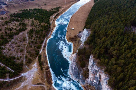 Top down view from drone over snowy river valley with partially frozen river.の写真素材