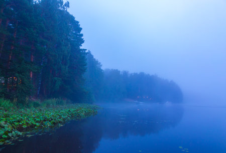 Wooden bridge made of boards on calm lake, evening sky and fogの写真素材
