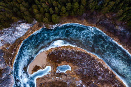 Top down view over snowy river valley with partially frozen river.の写真素材