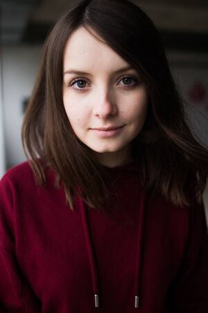 big eyes, sweet girl in burgundy hoodie, smiling and looking at youの写真素材