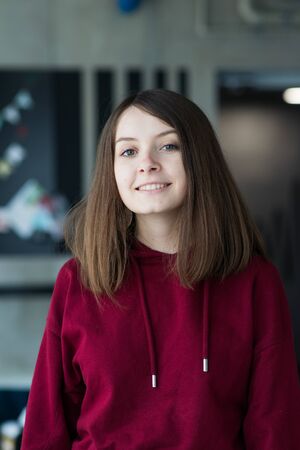big eyes, sweet girl in burgundy hoodie, smiling and looking at youの写真素材