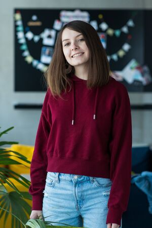 big eyes, sweet girl in burgundy hoodie, smiling and looking at youの写真素材