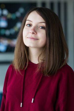 big eyes, sweet girl in burgundy hoodie, smiling and looking at youの写真素材