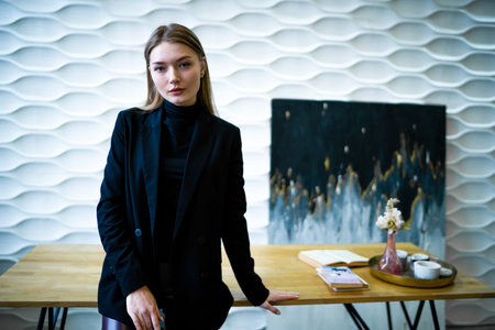 Business woman standing near the table in a black jacket
