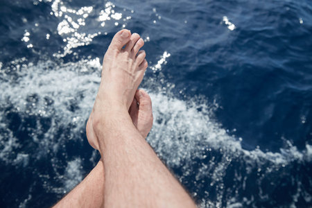 Bare feet hang down over azure water, splashes, sun patches of light on water,  sailing, sunny...