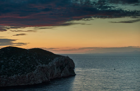 The lighthouse on the mountain at sunset, the orange sky, the quiet sea