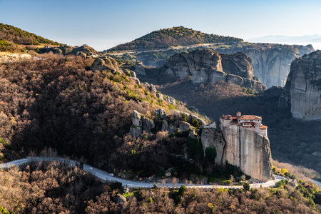 Aerial view of monastery Rousanou and breathtaking picturesque valley and landmark canyon of Meteora at sunset, Kalambaka, Greece, shadows, twisted road, bridgeの写真素材