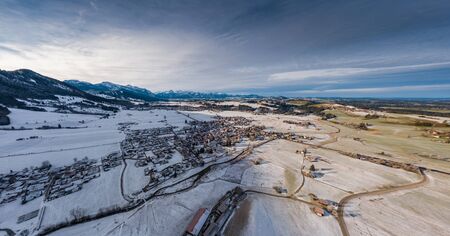 Aerial view of the small cozy german town at the mountain bottom at sunrise in a winter season, Halblech city, Germany, Bavaria, Branches of trees are covered with hoarfrost, sunny weatherの写真素材