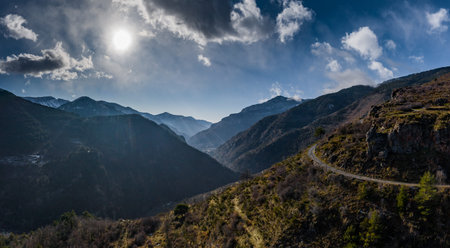 Aerial panoramic drone view of a scenic highway by the beautiful Landscape covered in clouds and fog, bridge and viaduct, The mountain river along the road, Snow-covered mountains on a backgroundの写真素材