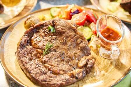 The big piece of the grilled meat and vegetables lies on a plate, Juicy beef steak, sauce, ultra hd qualityの写真素材