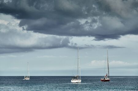 The Landscape of the balearic sea, azure water, the storm sky, lonely sailboats in horizon, cloudy weatherの写真素材