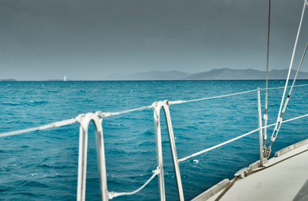 The view of the sea and mountains from the sailboat, edge of a board of the boat, slings and ropes,...