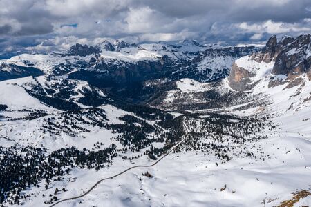 Aerial view of twisting road in mountains of Italy, Dolomites, is serpentine among the snow-covered hills, is famous place among skiers and fans to understand a known by sports cars, mountains peakの写真素材