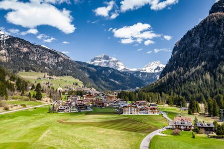 Aerial view of valley with Chalet, green slopes of the mountains of Italy, Trentino, Fontanazzo, huge clouds over a valley, roofs of houses of settlements, green meadows, Dolomites on background,の写真素材