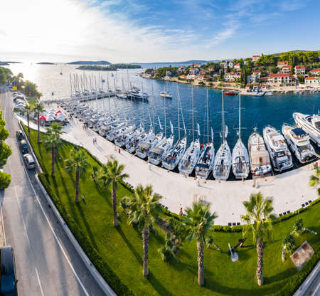 Croatia, Maslinica, 15 September 2019: Drone view point on moored in an equal row sailboats at sunset, participant of a sailing regatta, people have a rest after racing day, azure water, pierのeditorial素材
