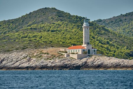 The lighthouse on the island in Croatia nearby Vis at sunset, a rocky coast, ladder to a beaconの写真素材