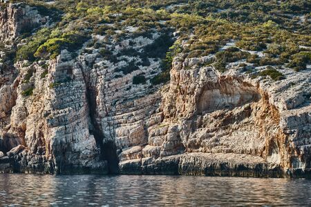 Beautiful high cliff with caves and hanging rocks of a mountain in Adriatic sea, a creviceの写真素材